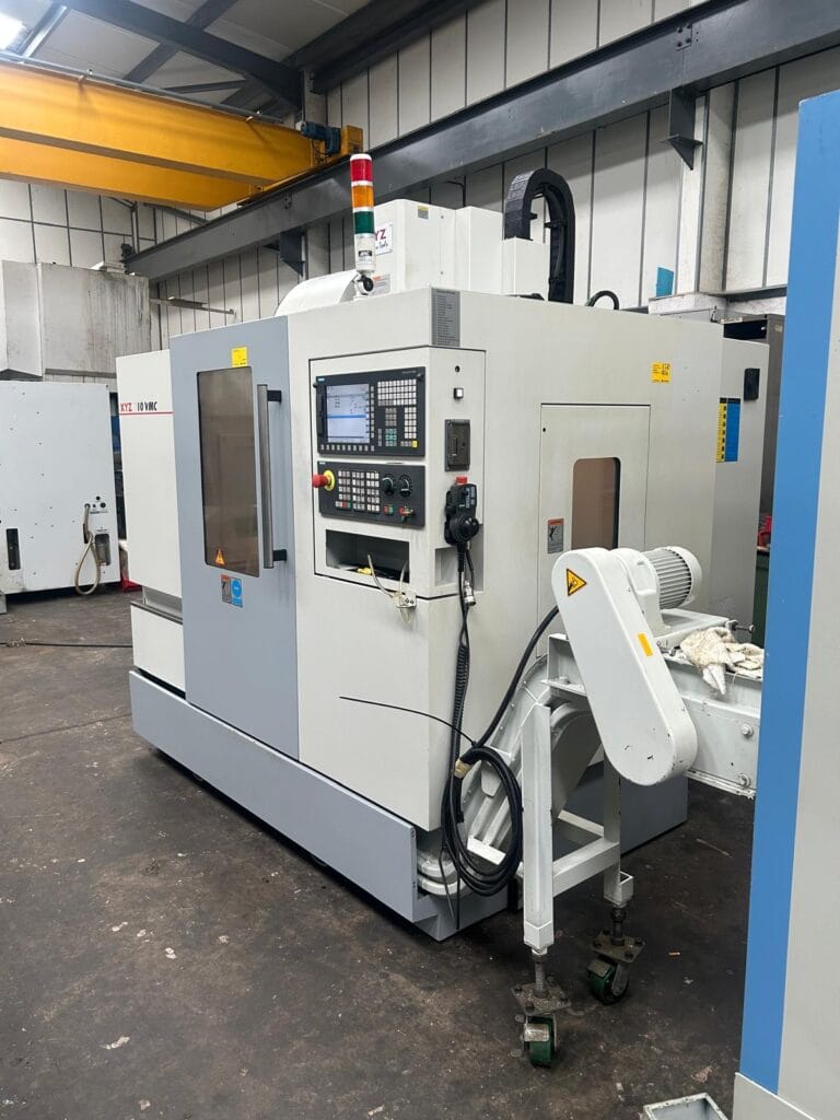 Side view of an XYZ 710 VMC vertical machining centre showing CNC control panel and chip conveyor